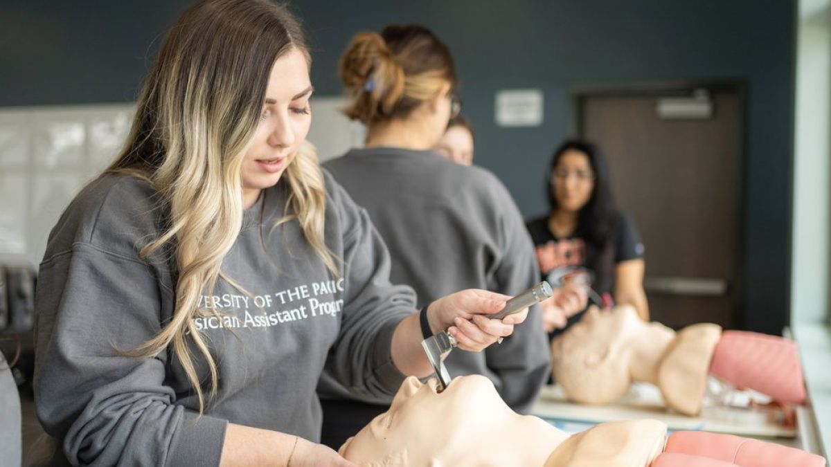 Image shows a PA student practicing a procedure on a mannequin.